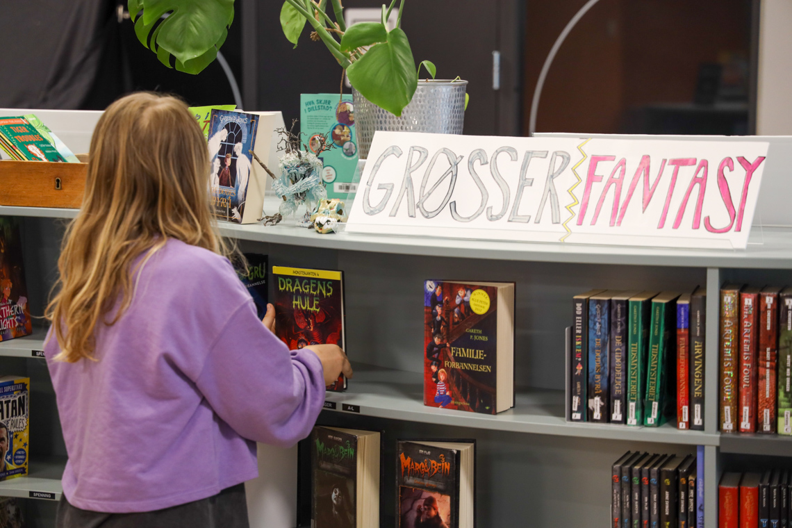 Jente leter etter bøker på skolebiblioteket.