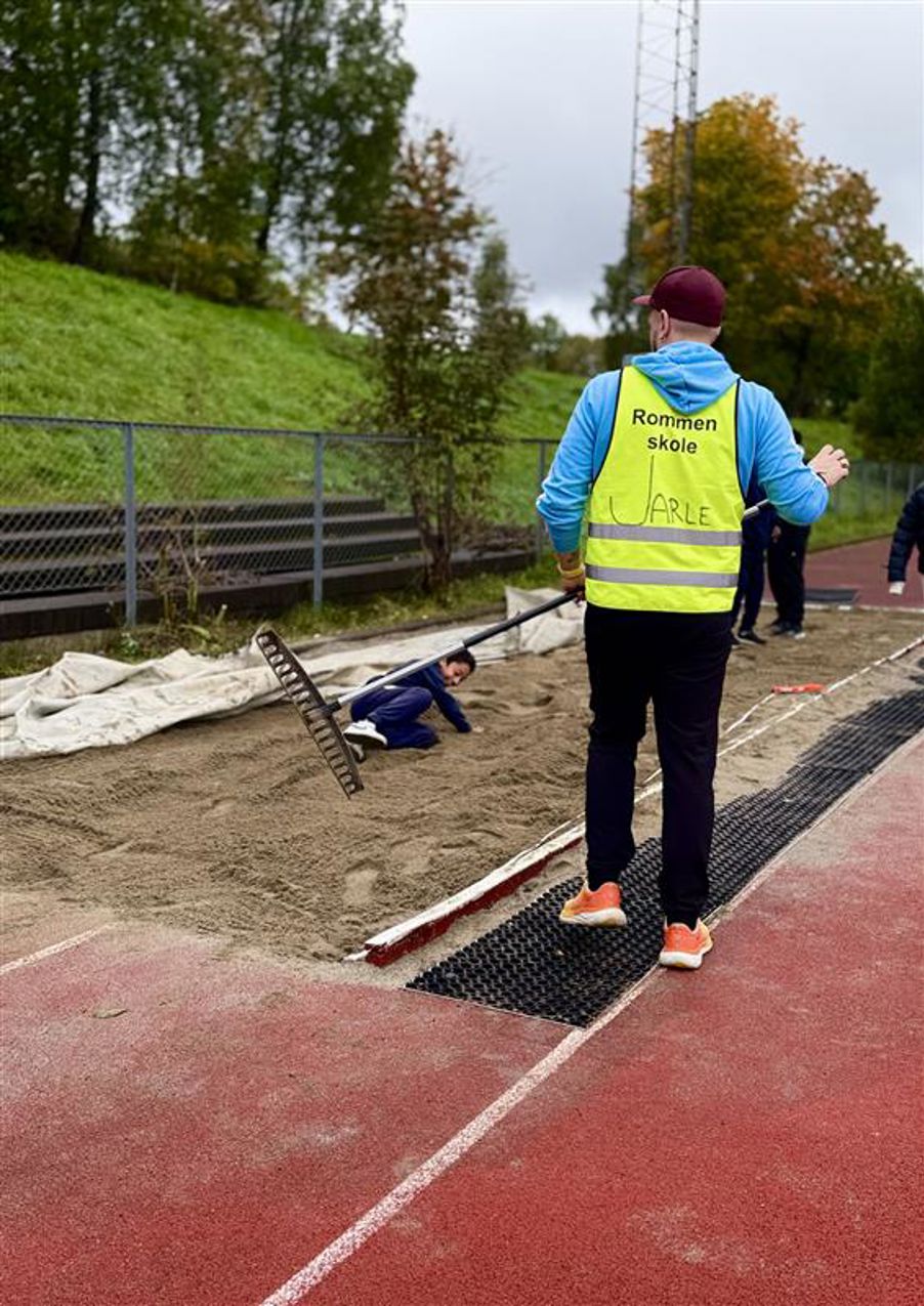 En person i gul vest og blå jakke som holder bue og pil
