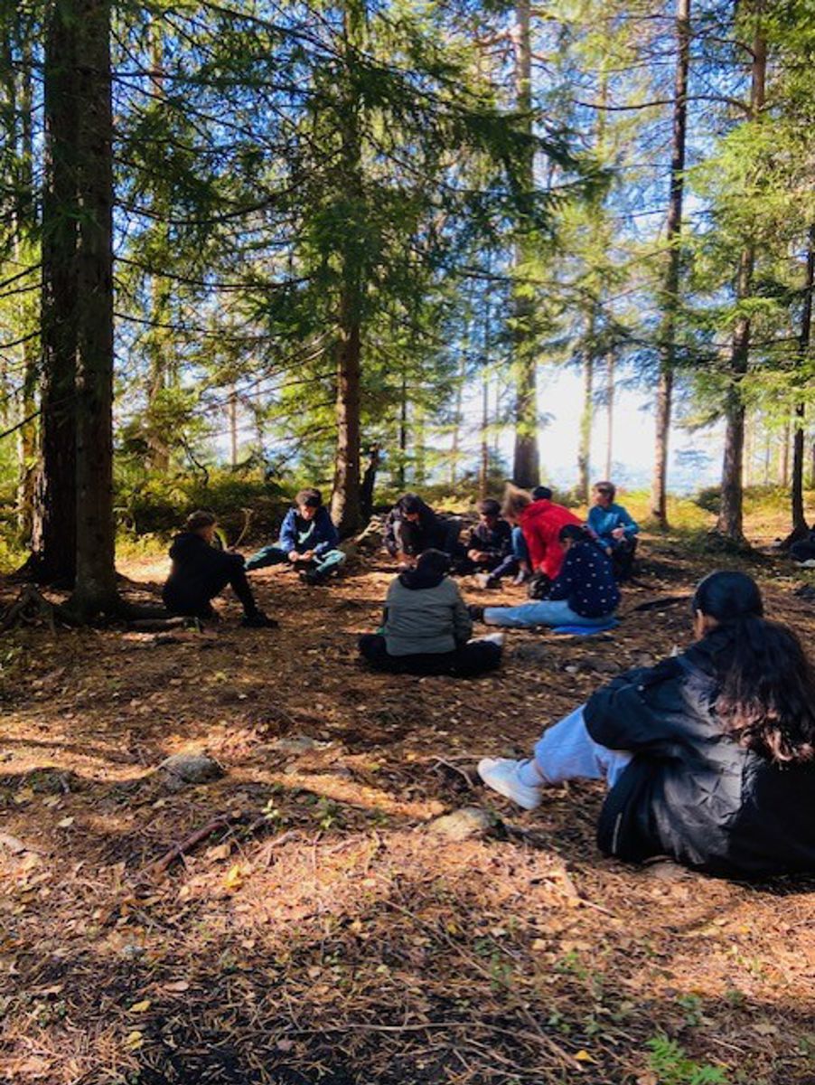 En gruppe mennesker som sitter i skogen