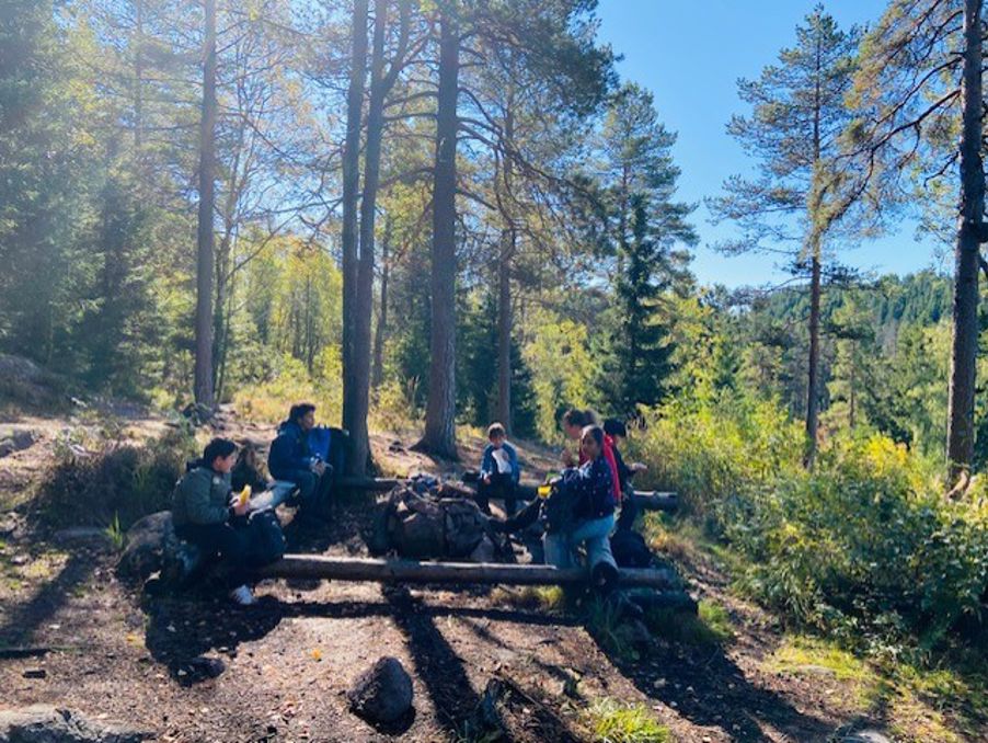 En gruppe mennesker som sitter på en benk i skogen