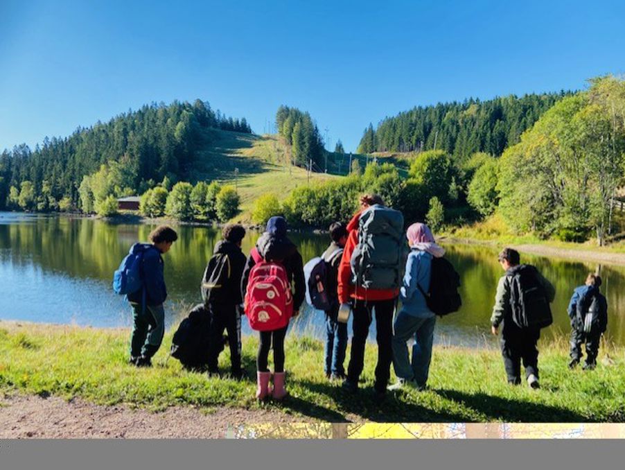 en gruppe mennesker som går på en sti ved en innsjø