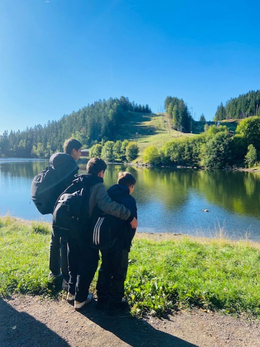 en gruppe mennesker som står ved en innsjø