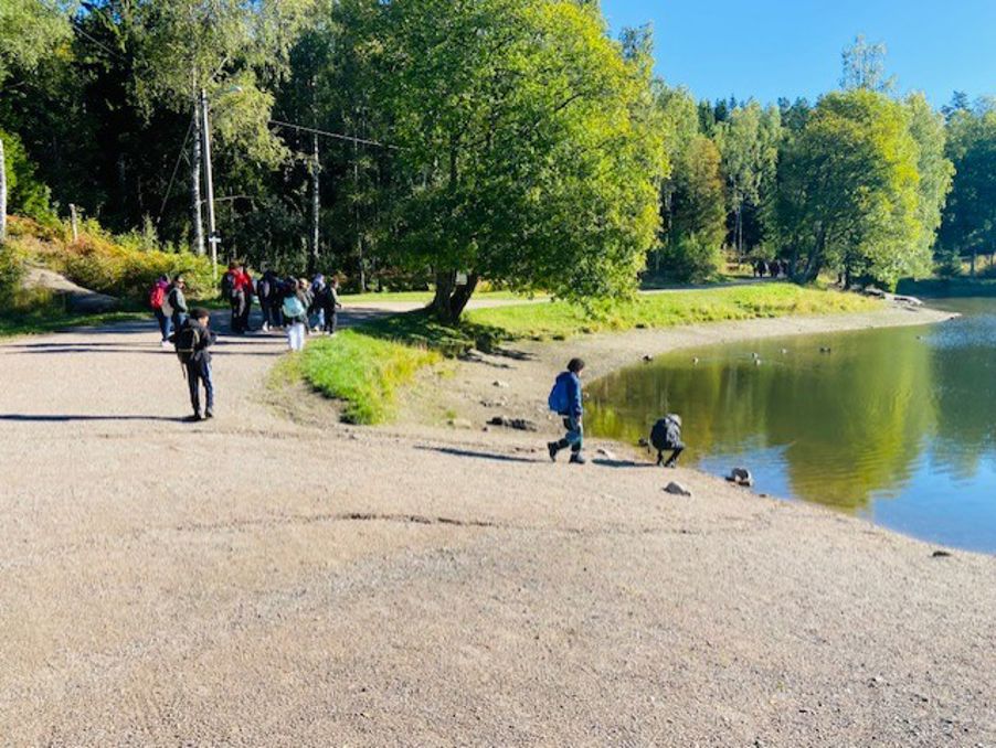 En gruppe mennesker som går langs en sti ved siden av en dam