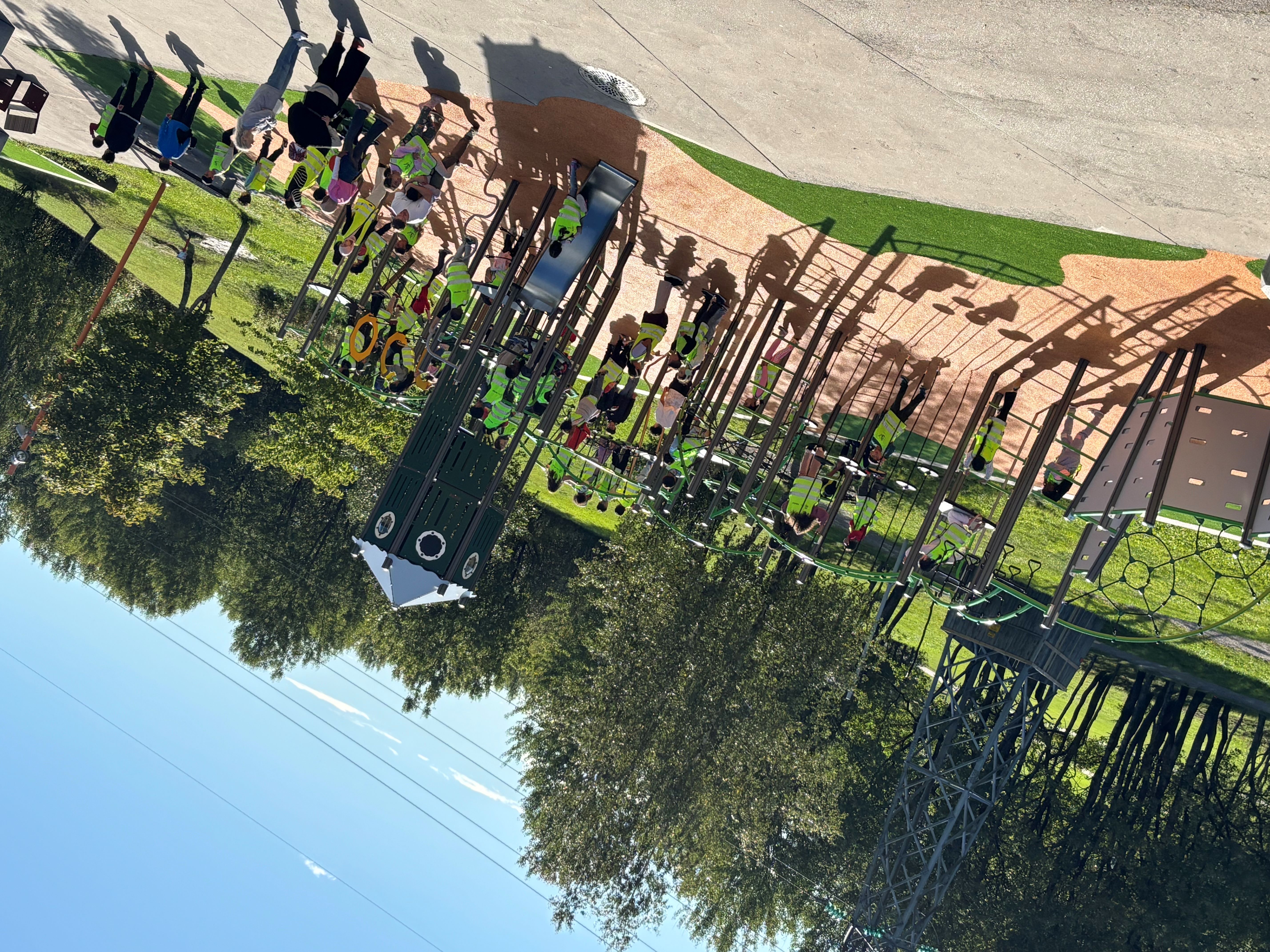 en gruppe mennesker som går på en sti med trær og en lekeplass