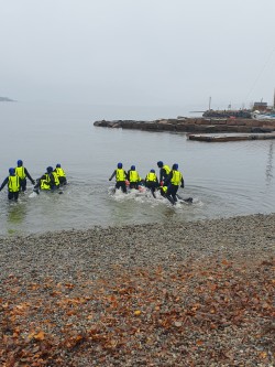 En gruppe mennesker i gule jakker som står i vannet