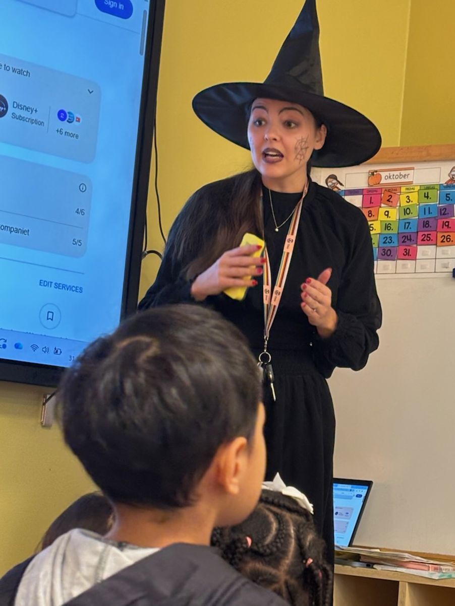 Foto: Katinka Bergersen Kvinge/Osloskolen en person som har på seg hatt og holder en gul gjenstand foran et barn